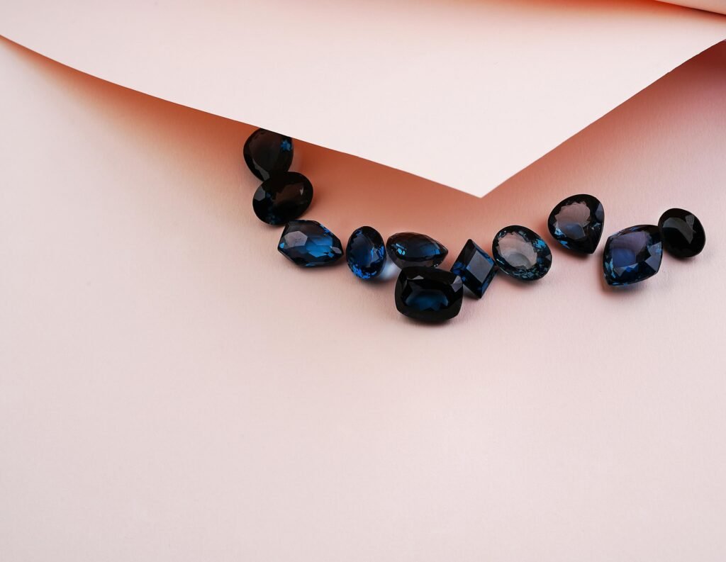 Luxurious set of blue gemstones arranged on soft pink paper surface.